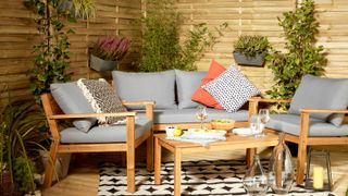 outdoor sofa with grey cushions and hit and miss fence