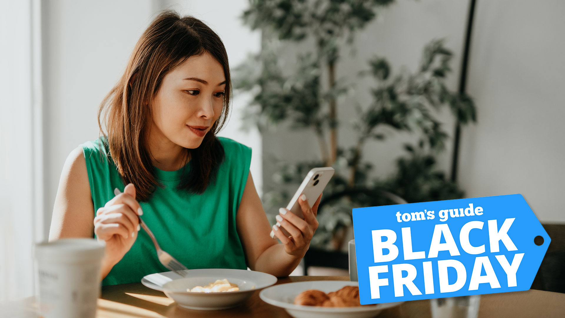 Woman looking at her phone while eating breakfast with Black Friday deal badge overlaid