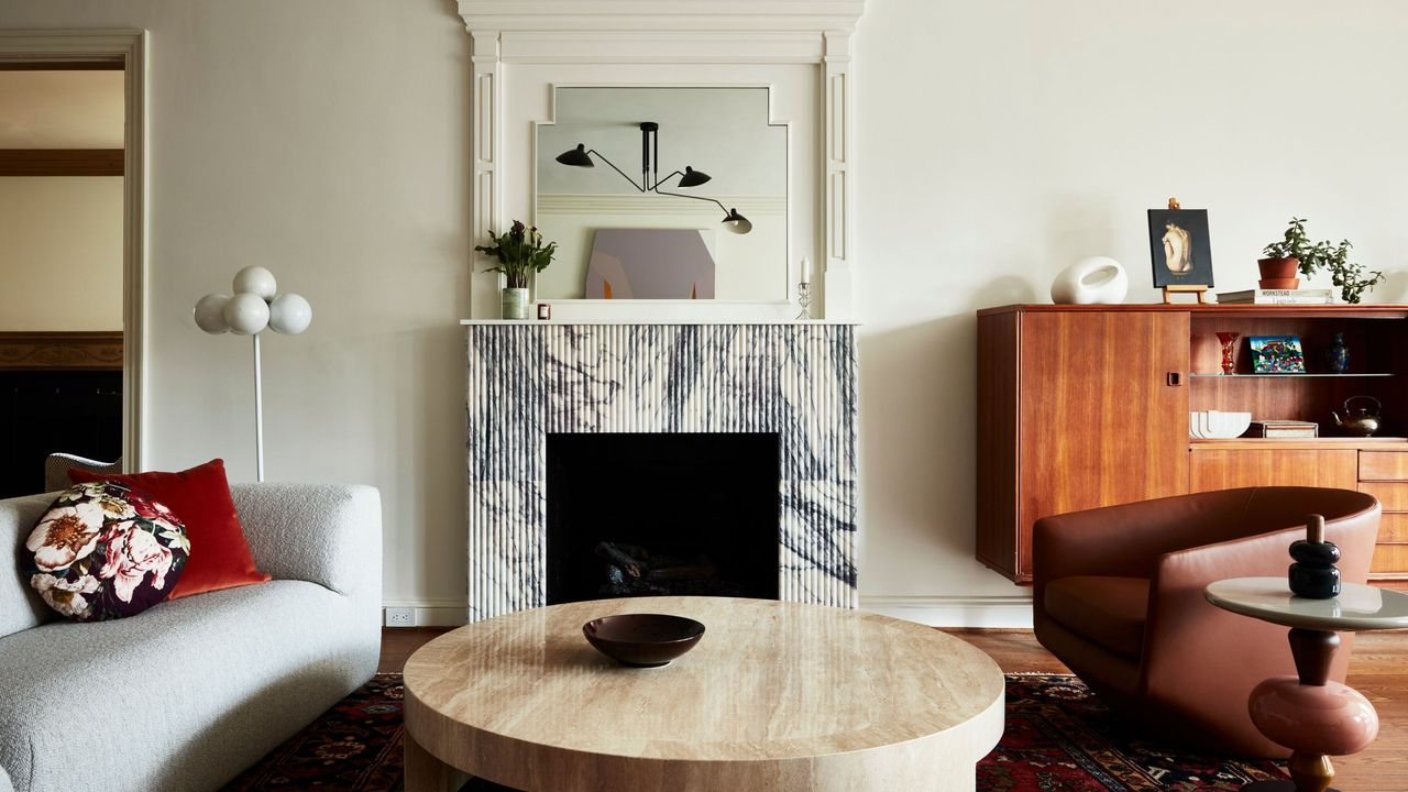 white living room with marble fireplace surround, white sofa, timber console, travertine coffee table