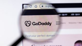 The GoDaddy website displayed inside a magnifying glass hovering over a browser window