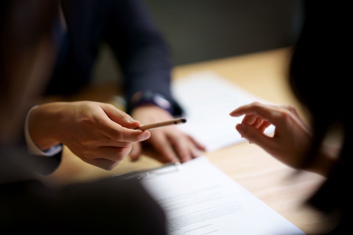 Architect handing pen to client to sign documents.