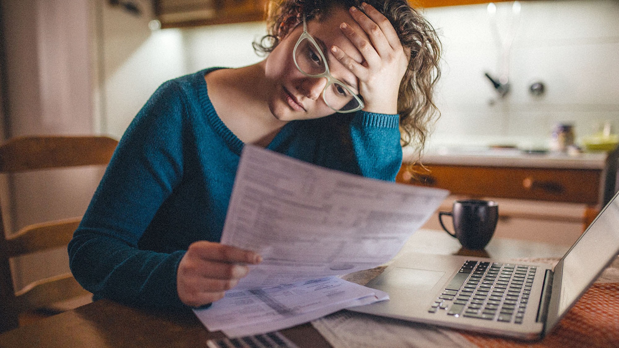 A concerned woman looks over her bills