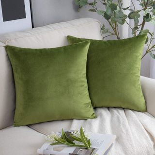 two green velvet pillows on a cream sofa with neutral decor