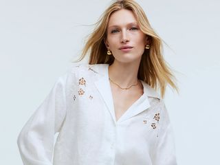 model wears white embroidered eyelet top with blue jeans
