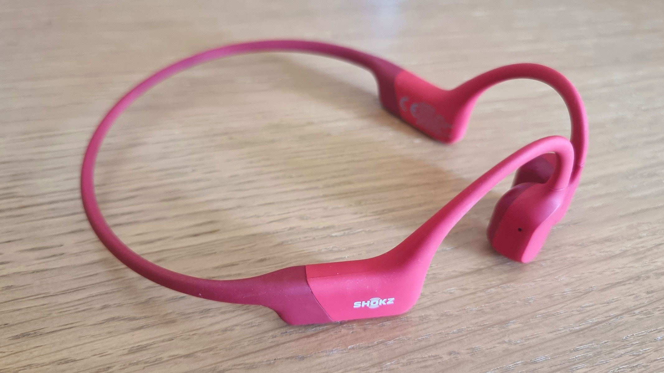 Red Shokz OpenRun bone conduction headphones on a table