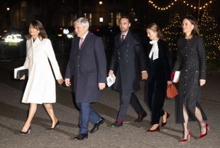 Carole, Michael, James, Alizee and Pippa Middleton wearing dressy coats and suits walking outside in front of Christmas trees in the dark entering a carol concert