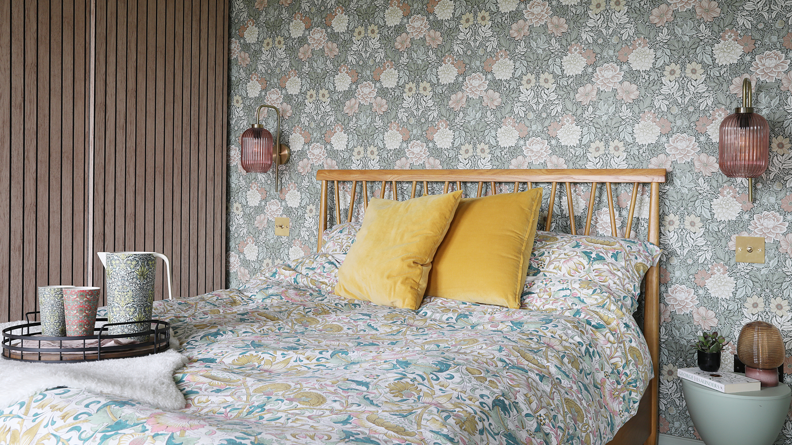 Double bed with William Morris floral bedding and two yellow decorative pillows.