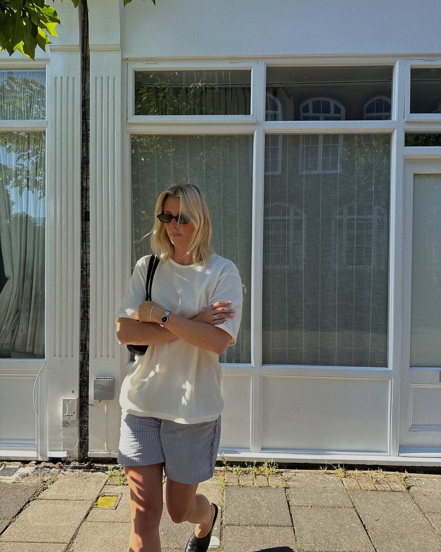 A woman standing outside in shorts and a t-shirt with a blonde bob hairstyle