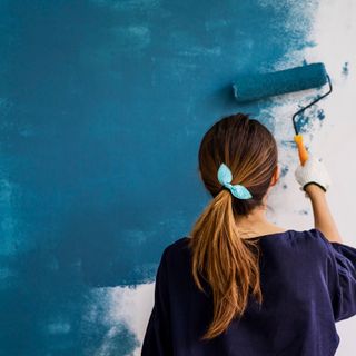 women paints wall with paint roller