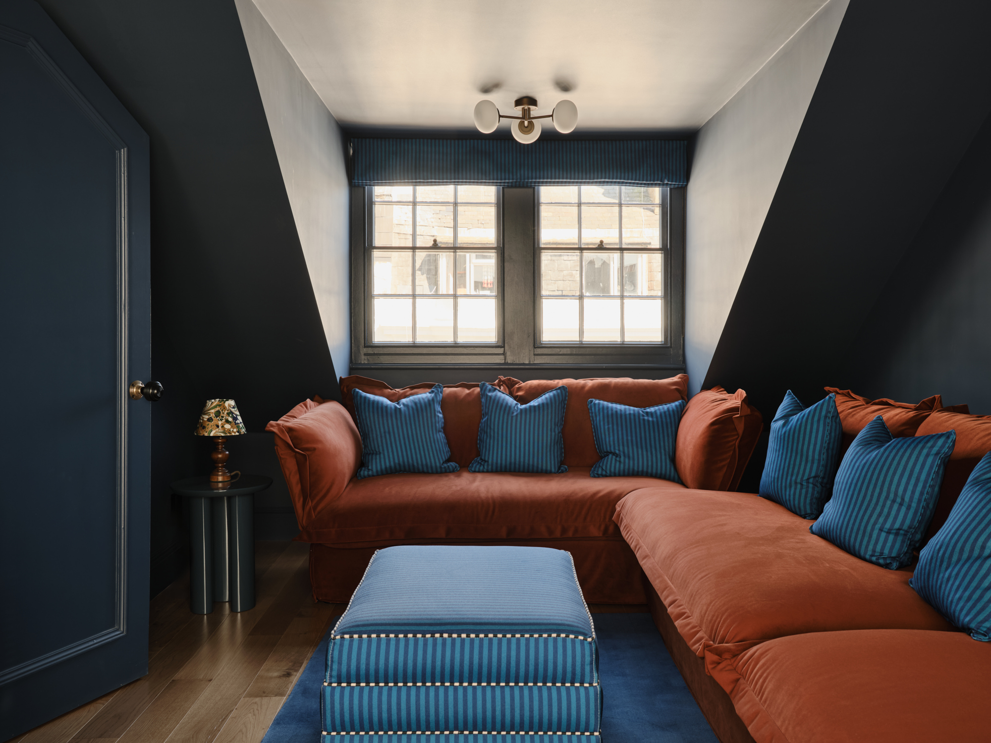 Living room by Appreciation Project with a sofa by King Living and a striped footstool at the centre