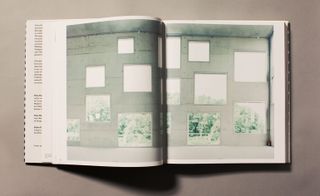 Open book with an image of large square windows on a concrete wall overlooking a forest.