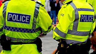 Two police officers wearing fluorescent jackets standing with their back to the camera