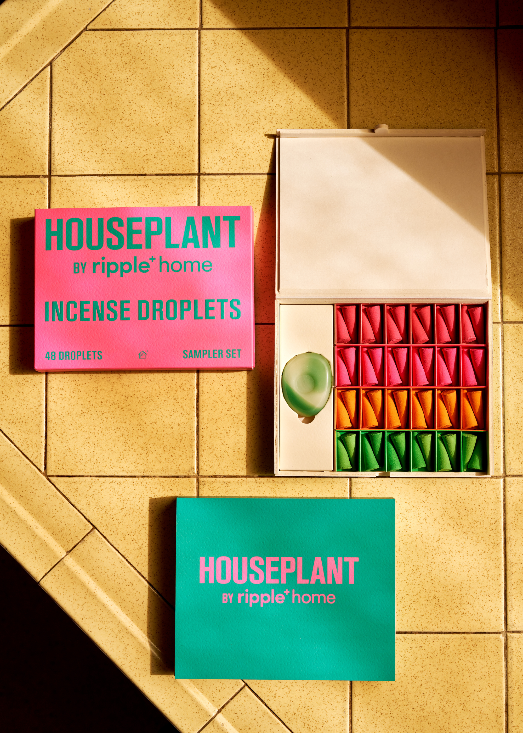A box of red, pink, orange, and green incense cones on a tiled counter
