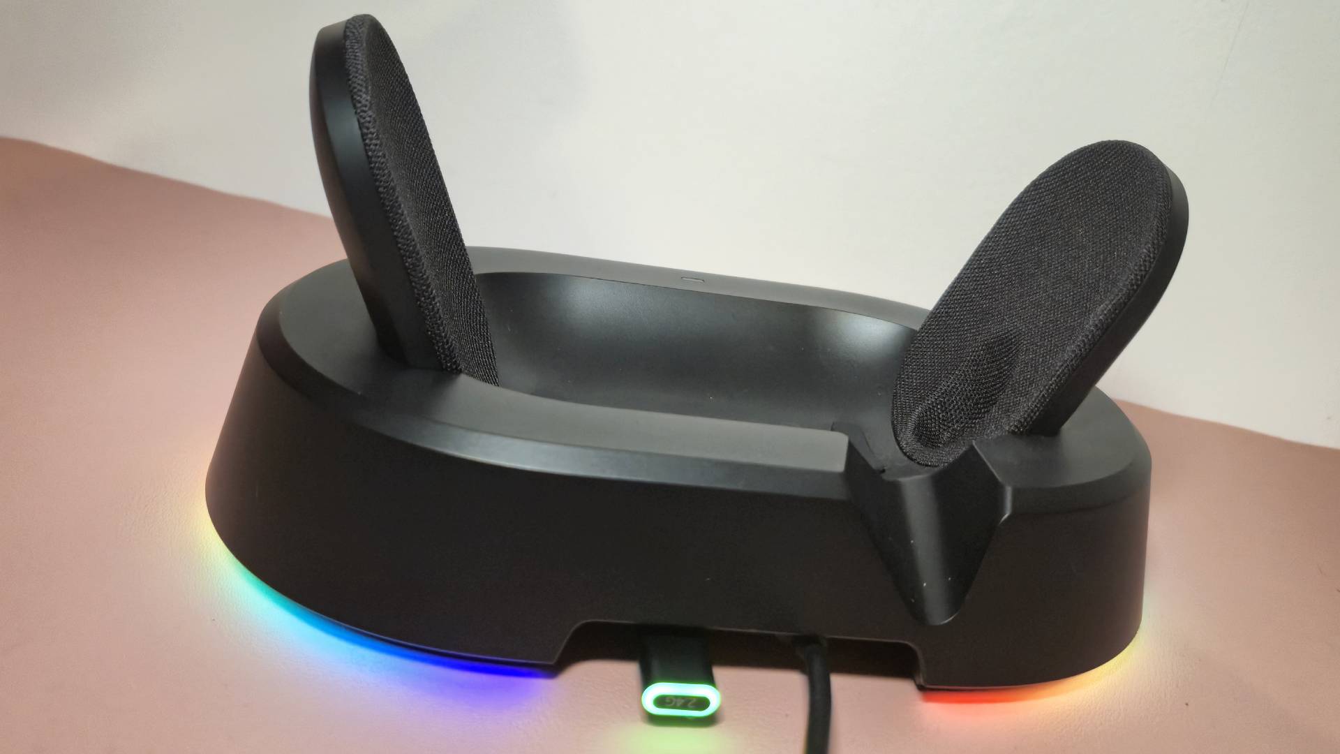 Photo of the charging stand of the Mchose V9 Turbo sitting on a pink desk mat.