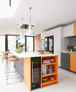 A modern kitchen design with kitchen island painted in grey and bright orange with wine fridge and ample shelf storage