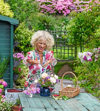 Gardener Sue Kent arranging flowers in a vase, in her garden