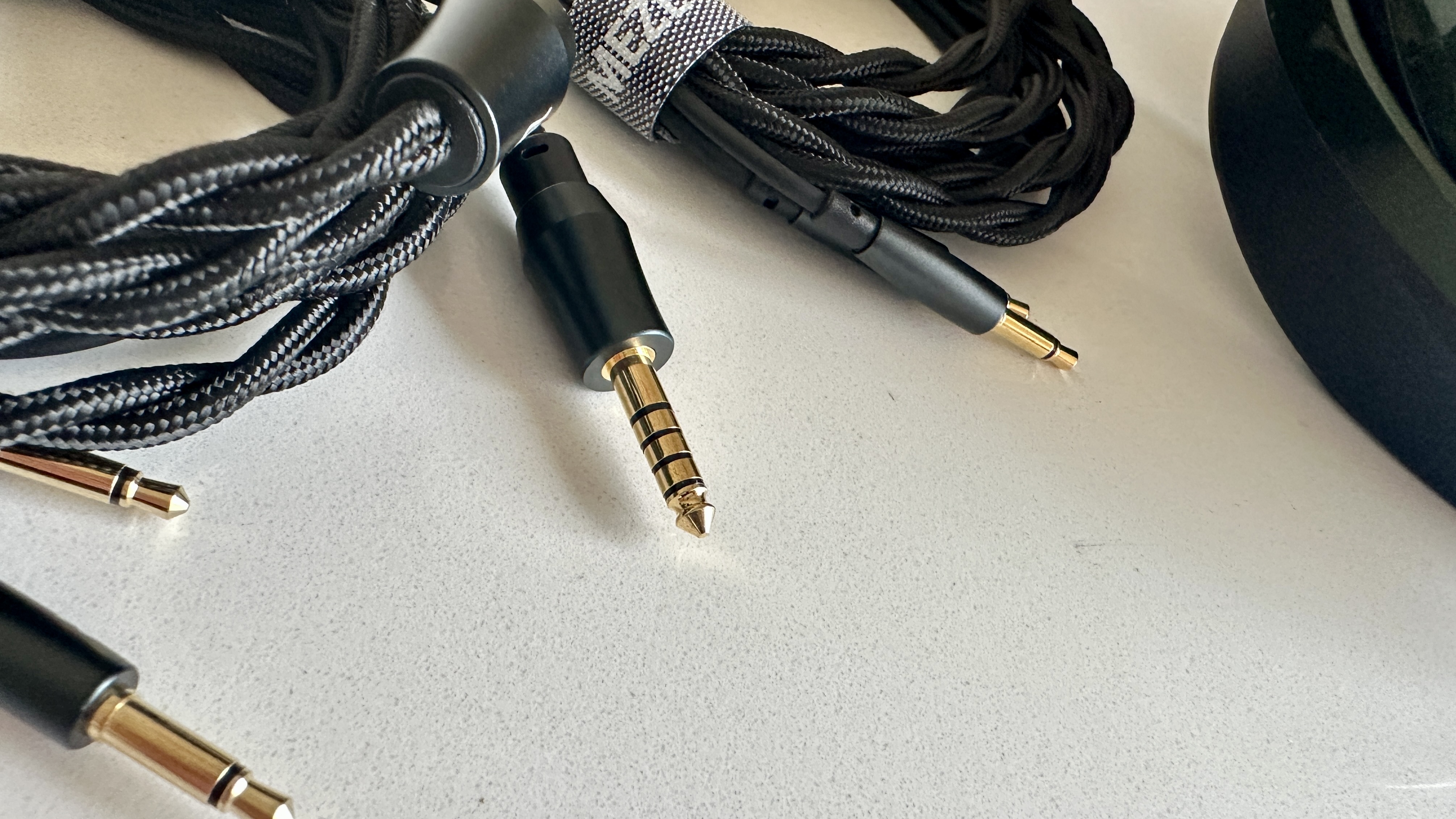Meze Audio Strada headphones with wooden ear cups, in close-up and with their case and cables visible, on a white table
