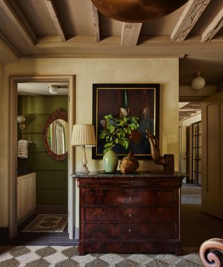 A Canadian chalet hallway decorated with an antique mahogany dresser and a checkerboard rug