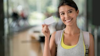 A woman holds up a gym card