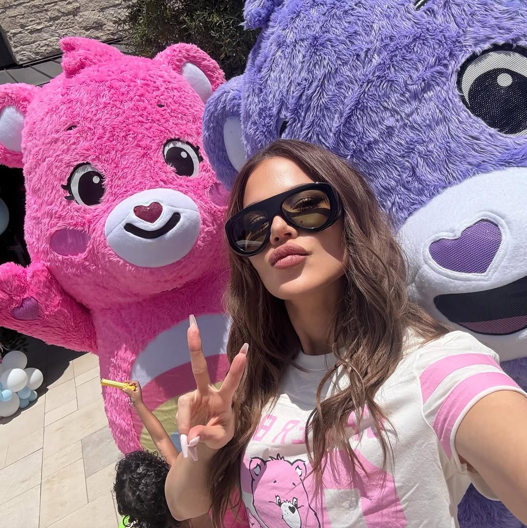khloe kardashian posing with two pink and purple care bears