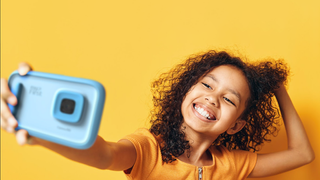 Child taking a selfie with the myFirst Camera 50 in front of yellow backdrop