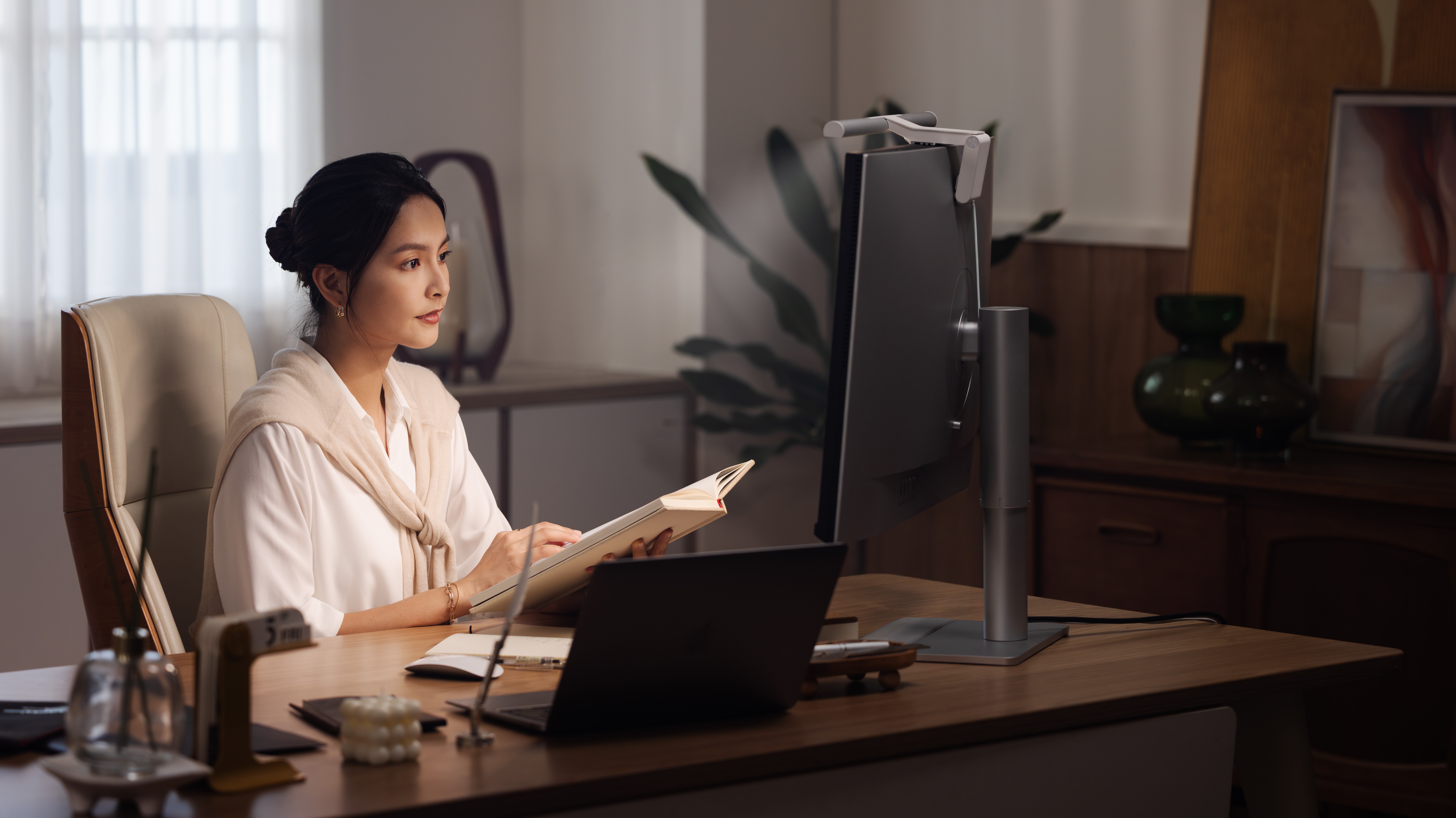A woman working at her desk, lit by a BenQ Screenbar Pro light.