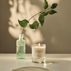 The Verde signature candle netxt to a small vase.