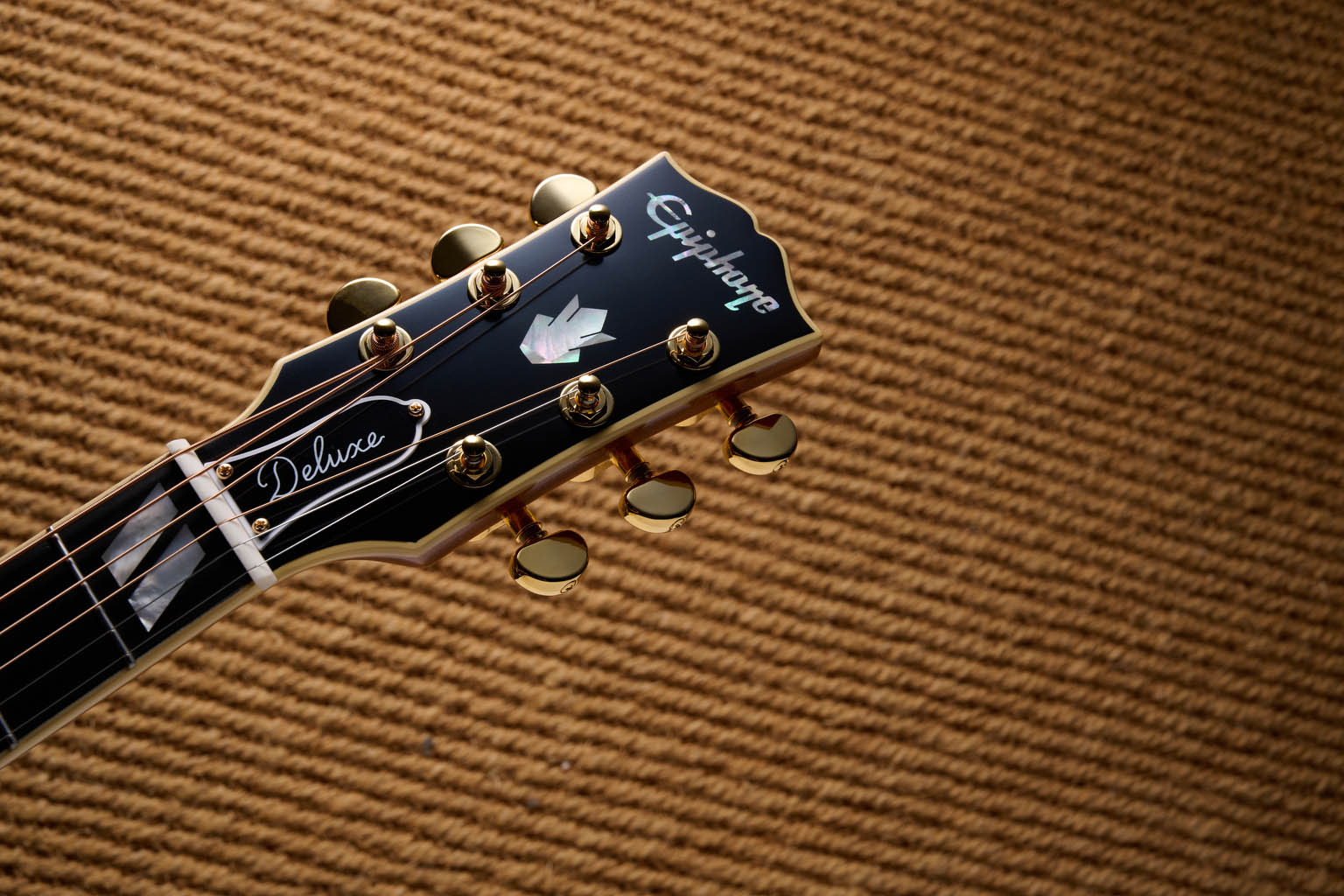 The Epiphone Inspired by Gibson Custom Hummingbird photographed in all its glory, in close-up and against a wheat-coloured rug.