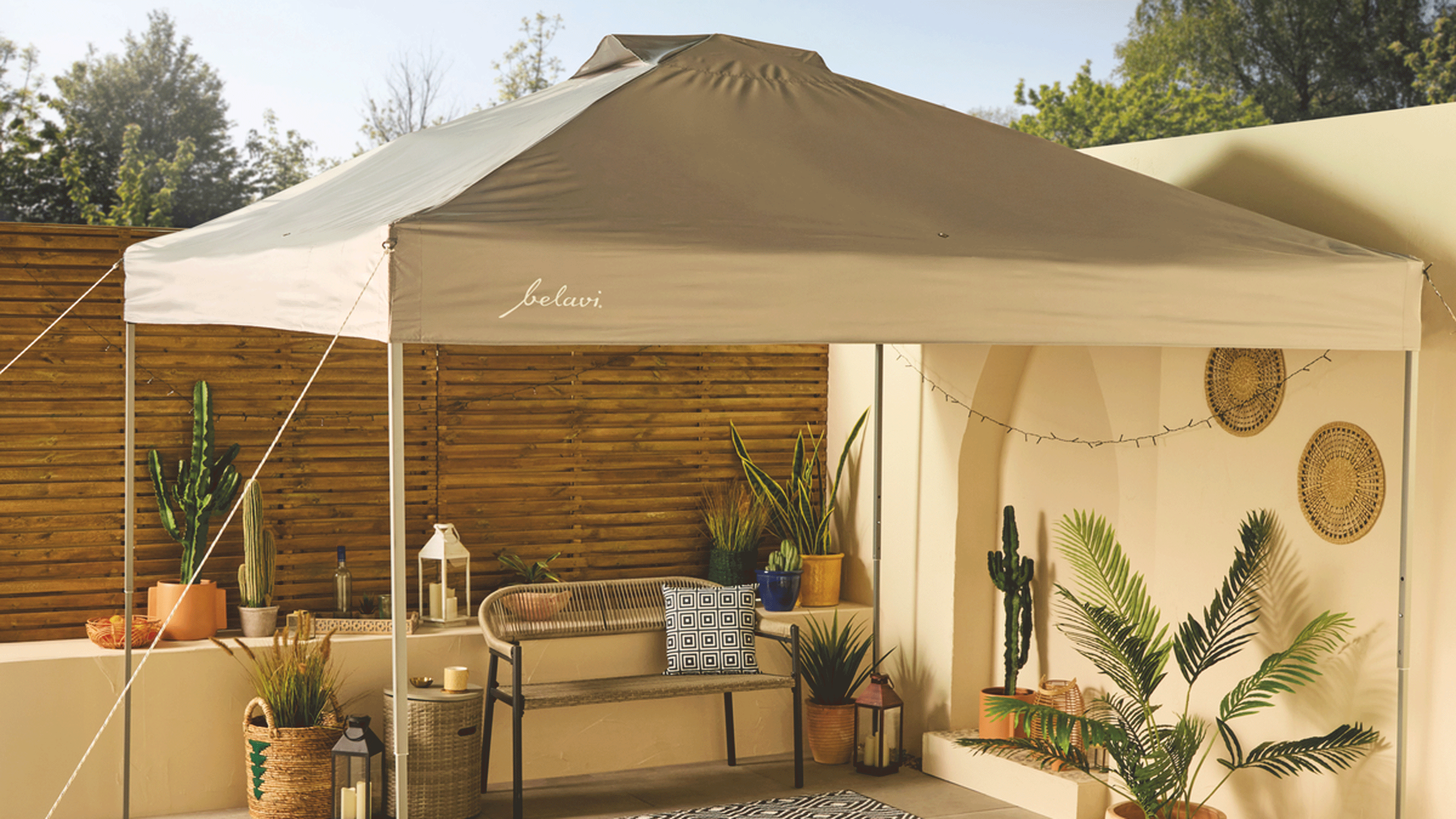 Aldi canopy set up over a patio garden with terracotta pots, plants and a wooden fence