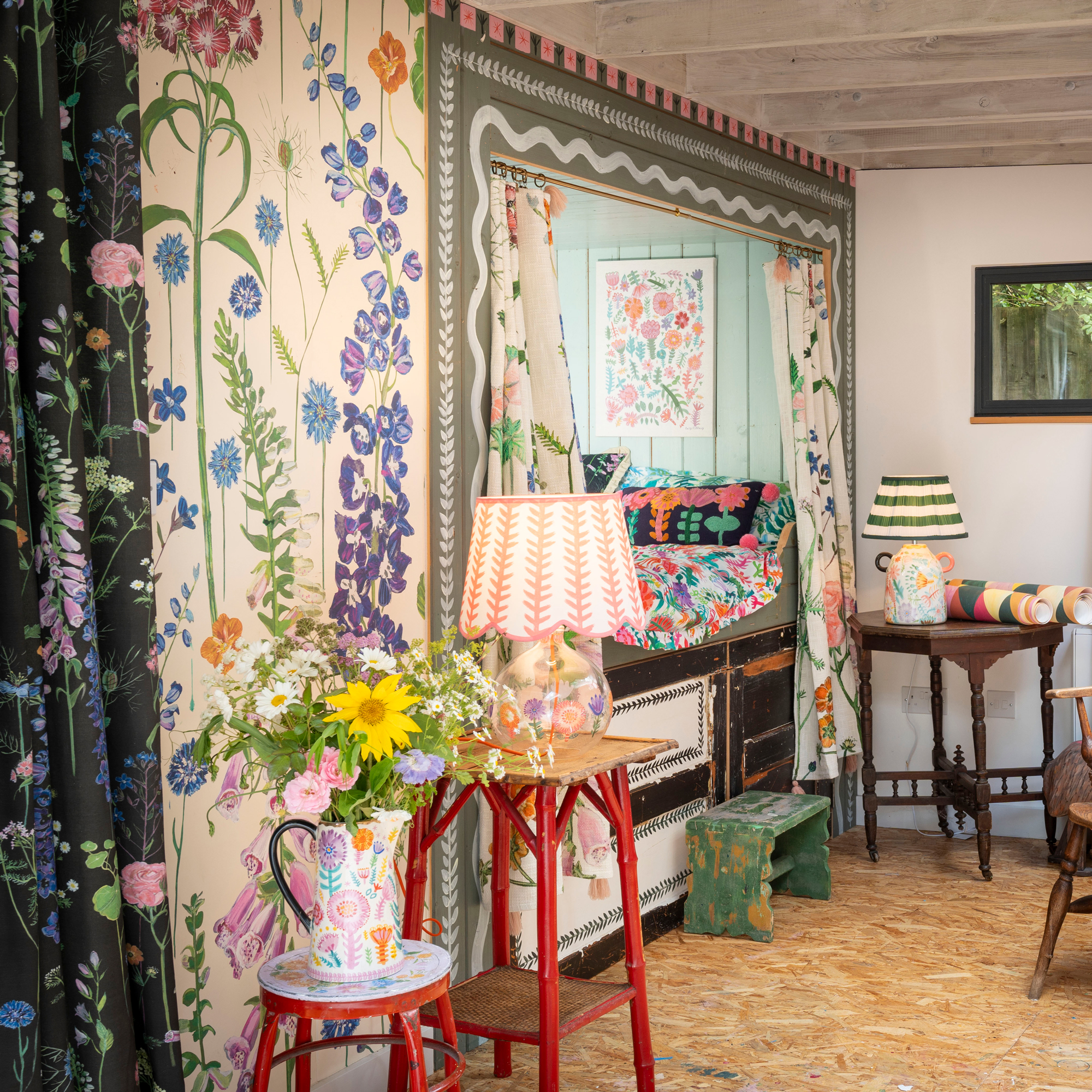 hand painted walls with a small built-in bed with floral curtains