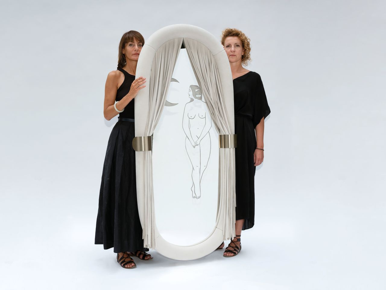 Studiopepe designer Chiara Di Pinto and Arianna Lelli Mami standing alongside their fringed mirror for Visionnaire