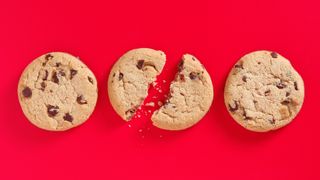 Three chocolate chip cookies on a red background. One broken.