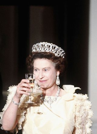 Queen Elizabeth II, wearing tiara and diamonds, makes a toast with former US President Ronald Reagan