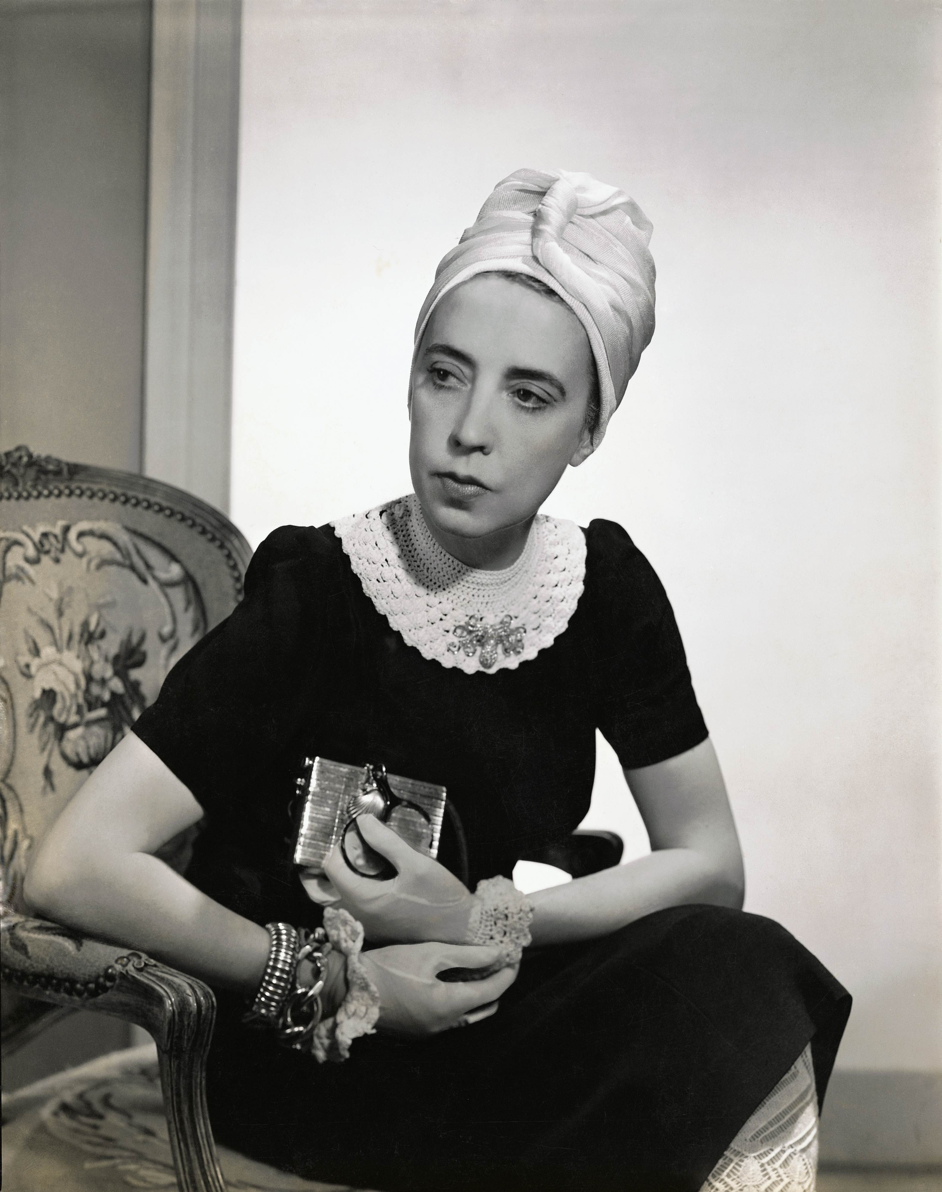 Designer Elsa Schiaparelli wearing black silk dress with crocheted collar of her own design and a tuban