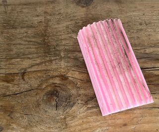 A dirty pink damp duster sponge on a wooden shelf