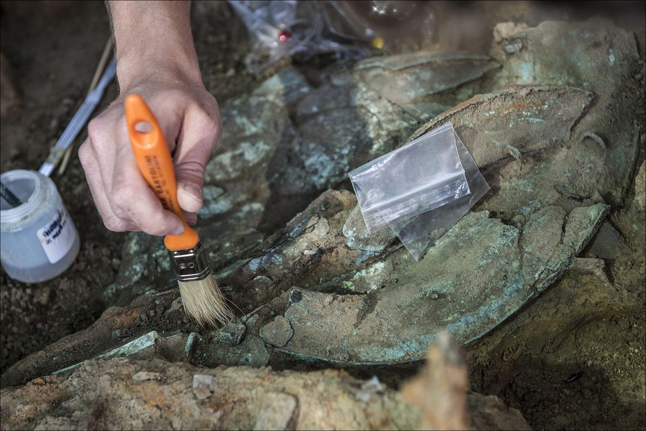 An archaeologist cleans the bronze helmet found in the Iron Age burial.
