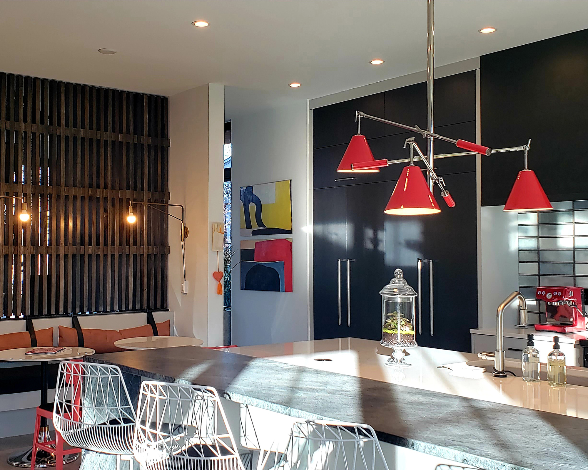 A contemporary kitchen design with trio of red ceiling lights around island