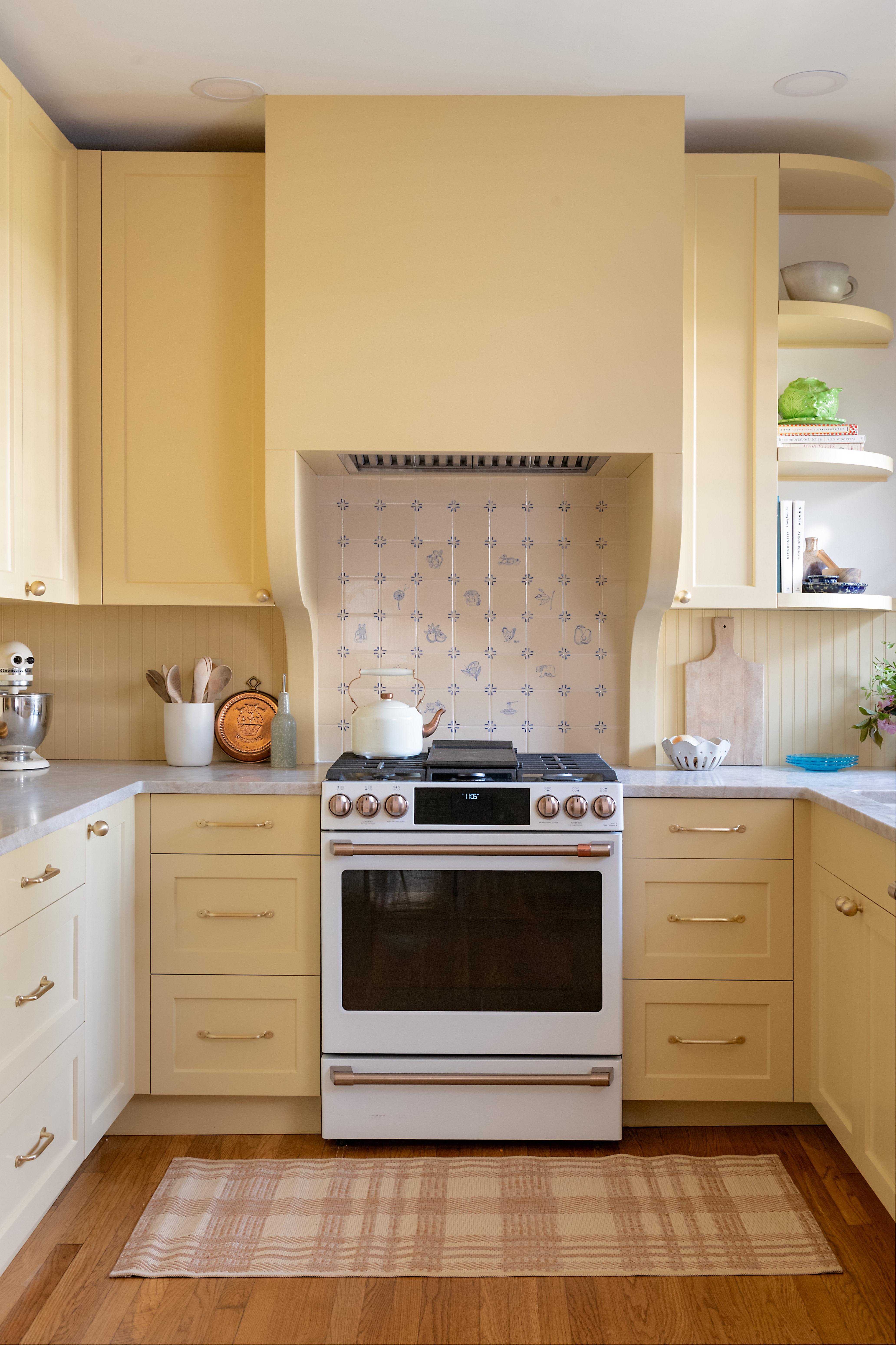 a butter yellow kitchen with white and blue tiles and a range cooker