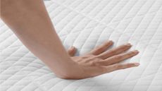 Hand pressing down on mattress