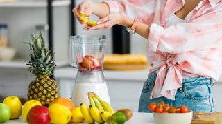 Woman adding fruit to a blender