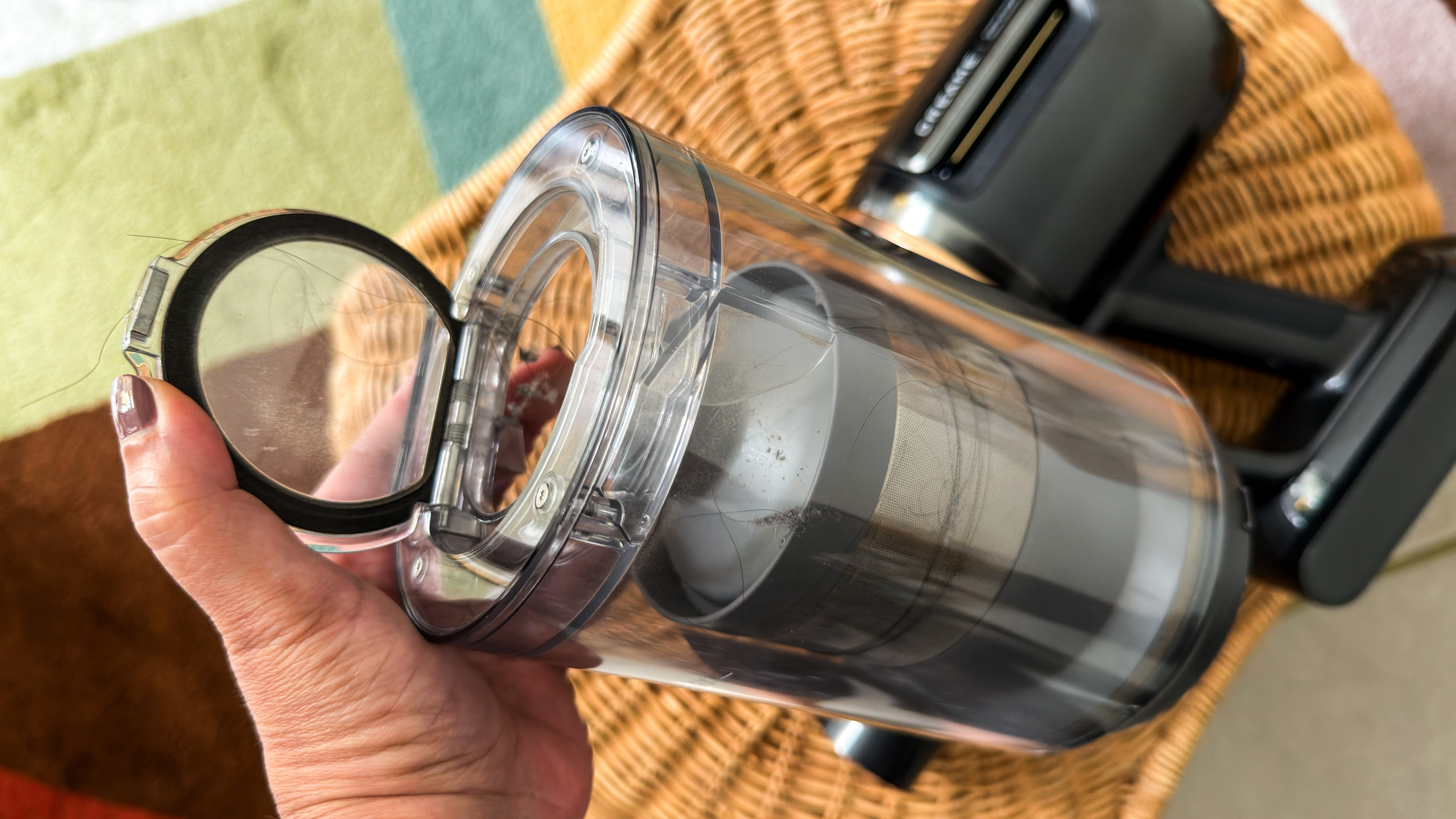 A person holding the Dreame Z50 Station dust cup open