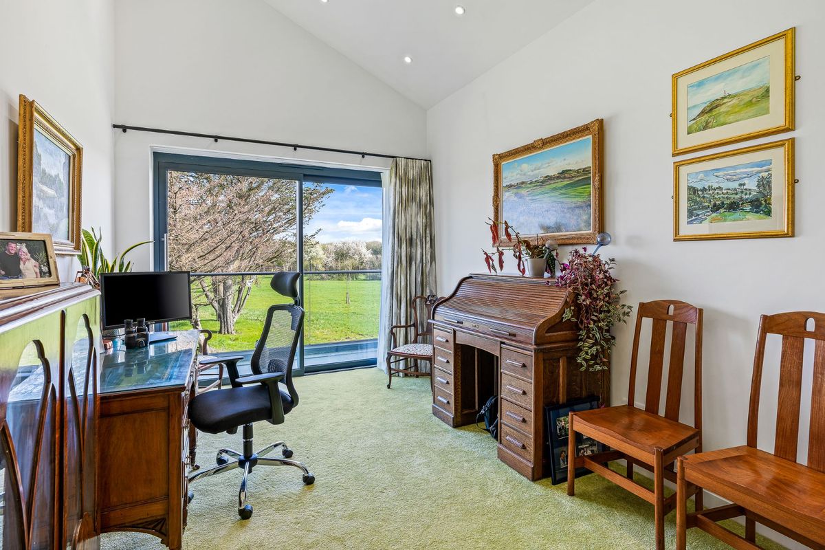 The home office has a wooden workstation, arts paintings on the wall and also leads out onto the balcony with views of the garden