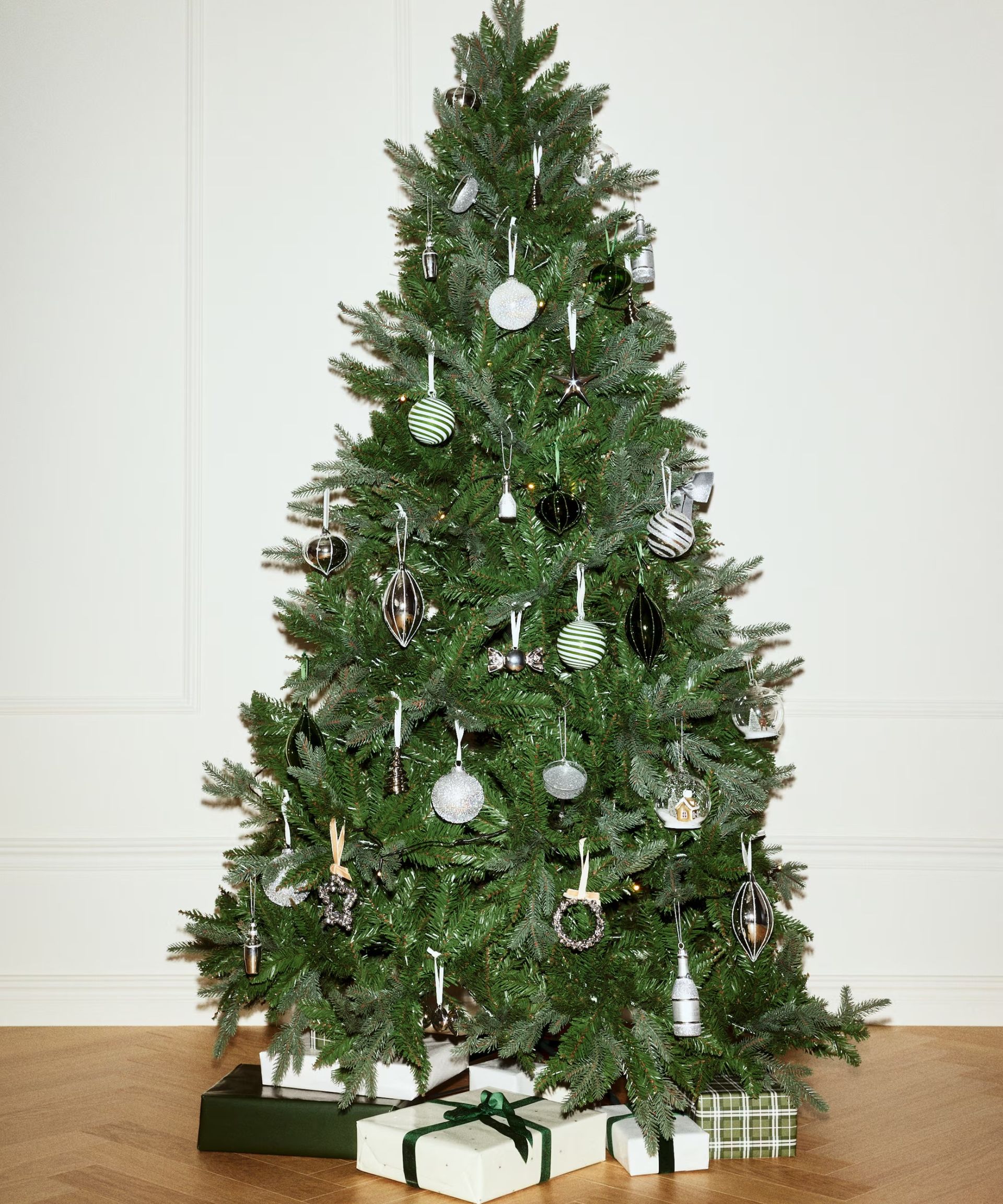 A Christmas tree decorated with H&M Christmas decorations including little silver jingle bell wreaths