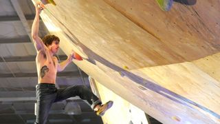 Daniel Woods hanging from an indoor climbing wall