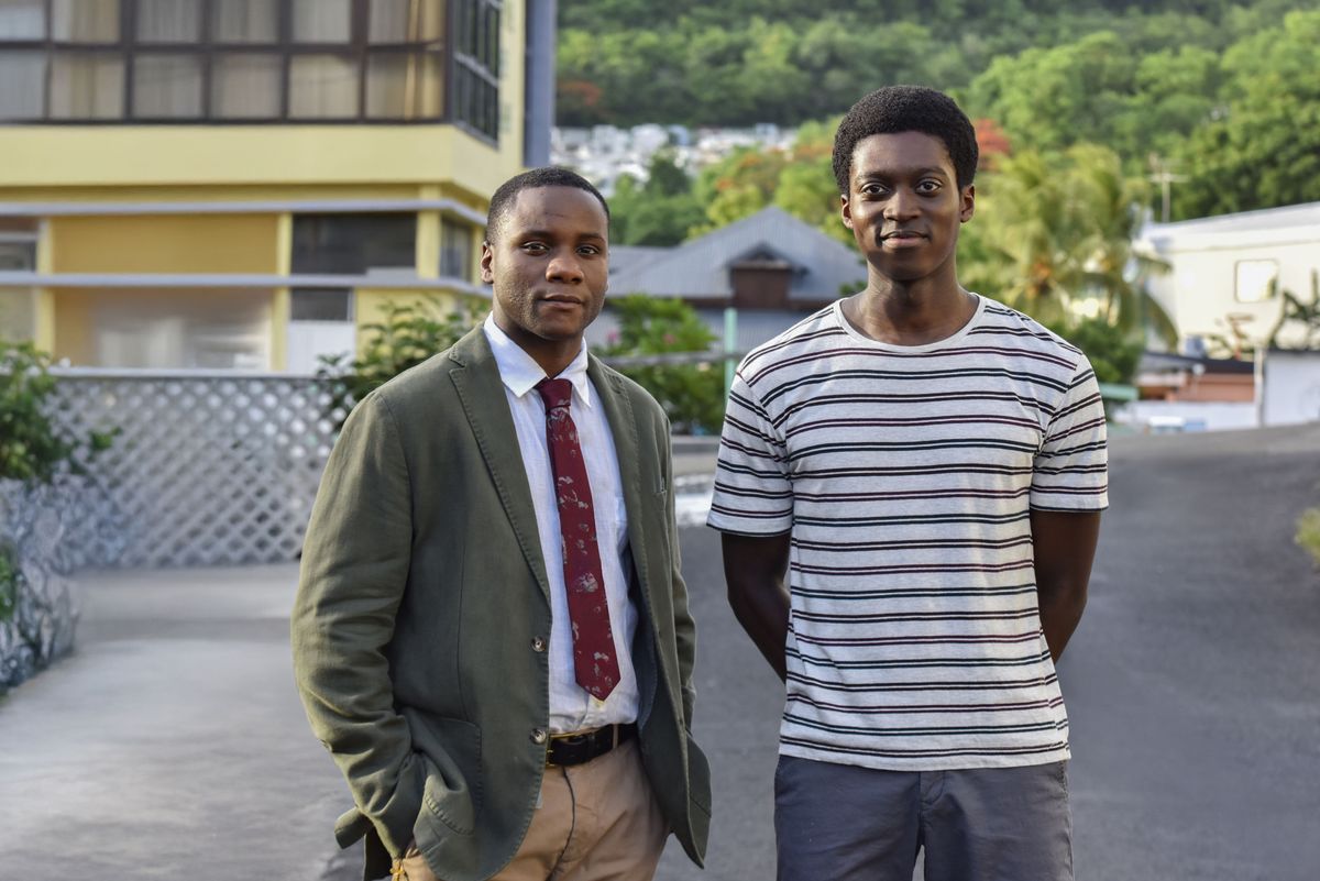 Sergeant JP Hooper (Tobi Bakare) and Benjamin Brice (Anthony J Abraham) stand in the street, looking into the camera. JP has his hands in his pockets and Benjamin has his hands clasped behind his back.