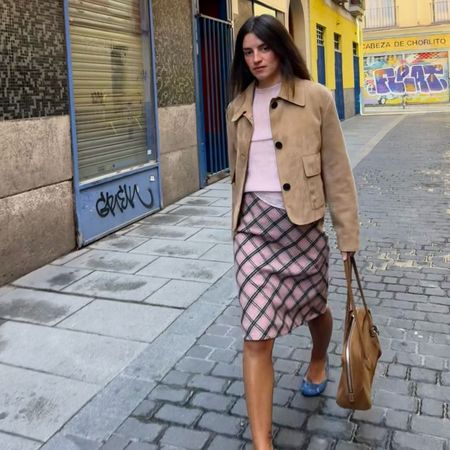Influencer @monpetitchuchu wears a pink paid skirt with a pink knit and brown suede jacket.