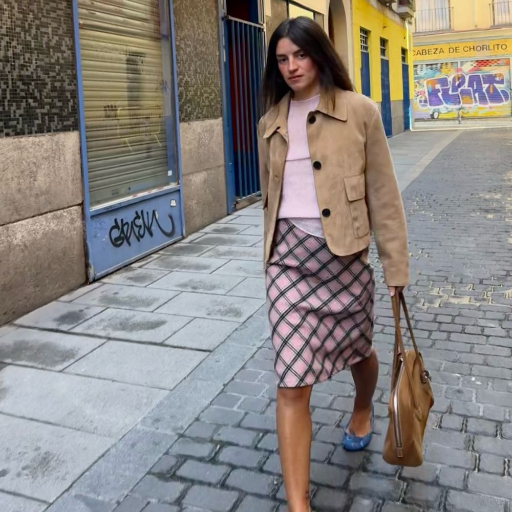 Influencer @monpetitchuchu wears a pink paid skirt with a pink knit and brown suede jacket.