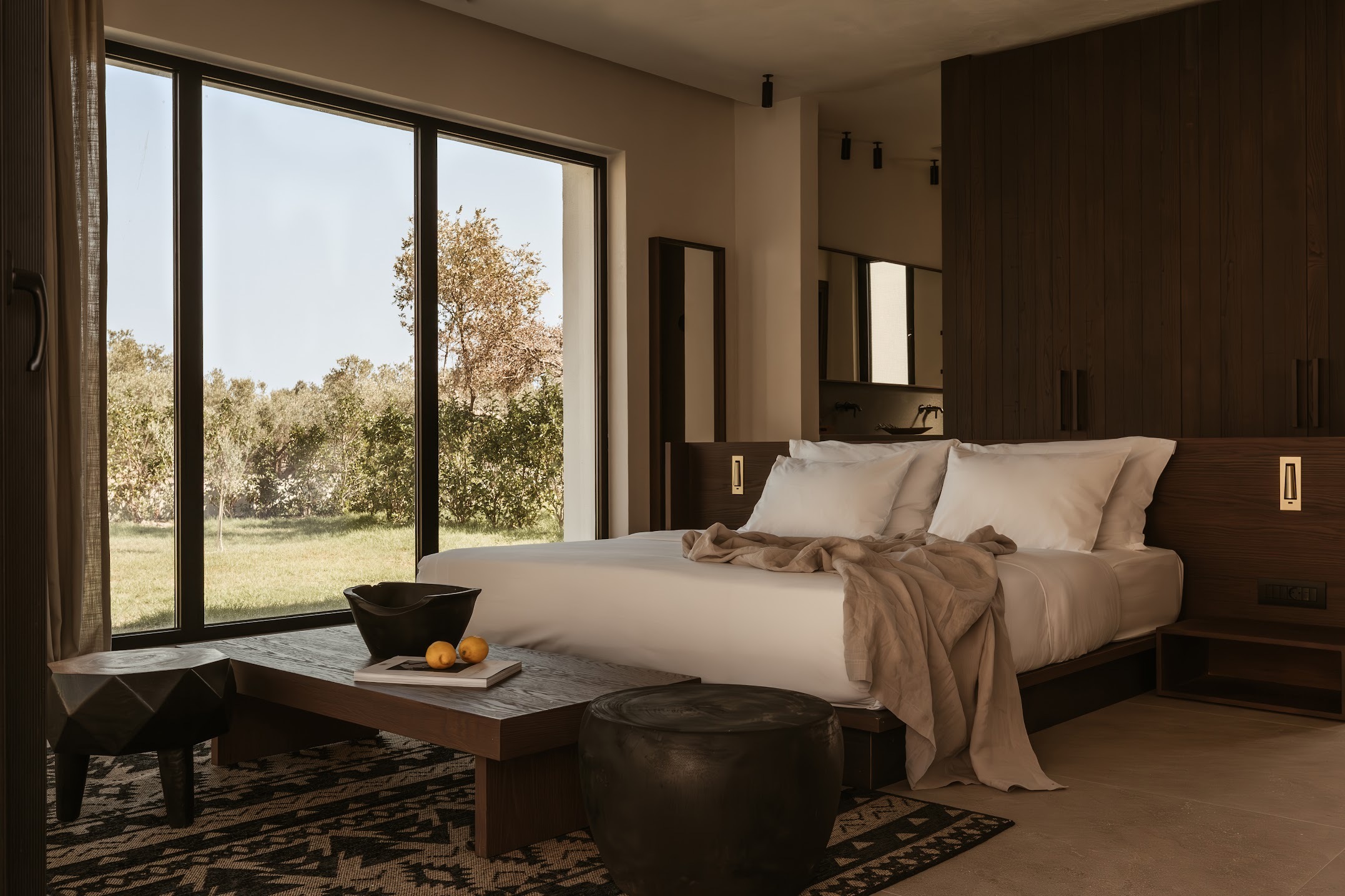 An organically decorated, modern rustic villa boasts wide views of the outside greenery, and wood and neutral textile tones.