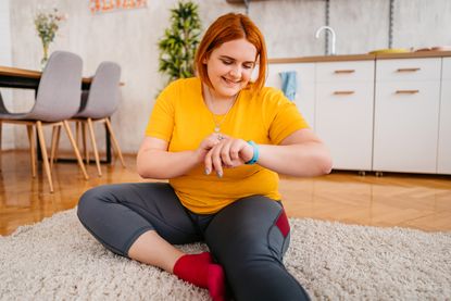 Woman at home timing herself performing new fitness resolution