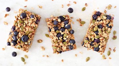 Blueberry flapjacks on a marble background with extra oats scattered on surface